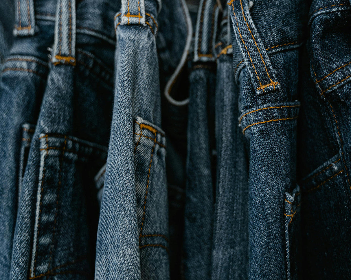 Vintage denim jeans på bøjler i secondhand butik